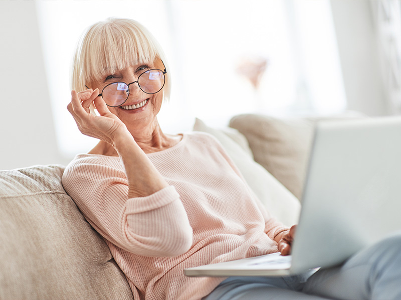 happy woman sitting on couch on her computer retirement planning strategies nashville tn